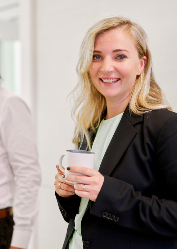 Woman in a suit smiling with a cup of coffee